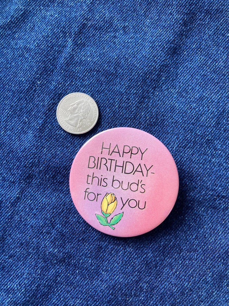 May include: A pink button with the text "Happy Birthday- this bud's for you" and a yellow flower illustration.