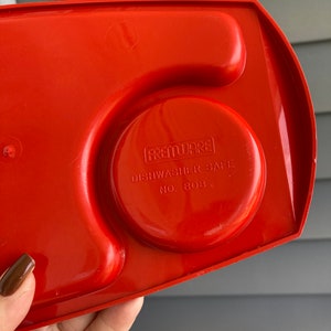 May include: Red plastic serving tray with three compartments. The tray has a circular indentation with the text "FREMWARES DISHWASHER SAFE NO. 808" printed on it.