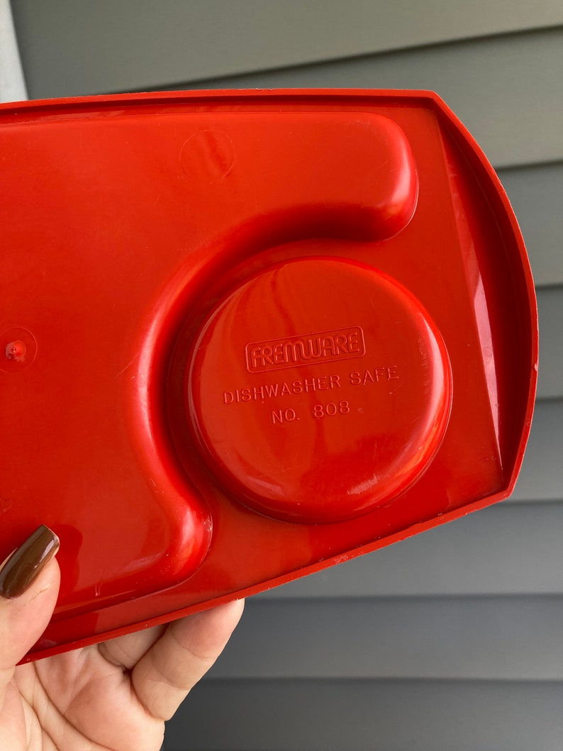 May include: Red plastic serving tray with three compartments. The tray has a circular indentation with the text "FREMWARES DISHWASHER SAFE NO. 808" printed on it.