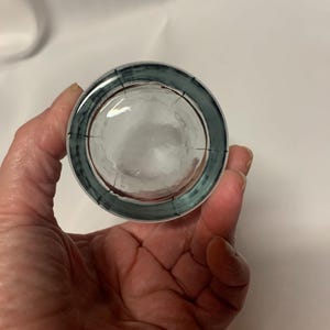 Puede incluir: Un vaso de chupito de vidrio transparente con un borde azul y rojo. El vaso tiene una superficie texturizada.