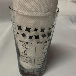 Puede incluir: Un vaso medidor de vidrio transparente con dise&ntilde;os de estrellas negras e instrucciones para hacer una margarita y un bloody mary. Las instrucciones incluyen los ingredientes y las medidas en onzas.