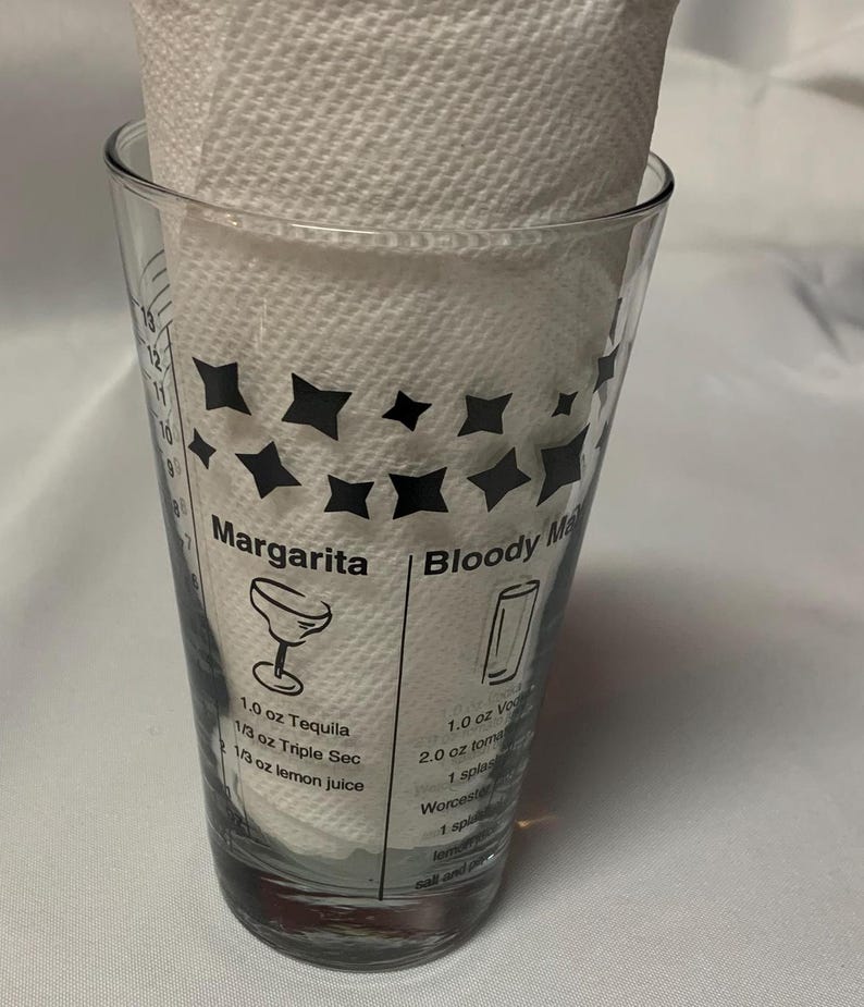 Puede incluir: Un vaso medidor de vidrio transparente con dise&ntilde;os de estrellas negras e instrucciones para hacer una margarita y un bloody mary. Las instrucciones incluyen los ingredientes y las medidas en onzas.