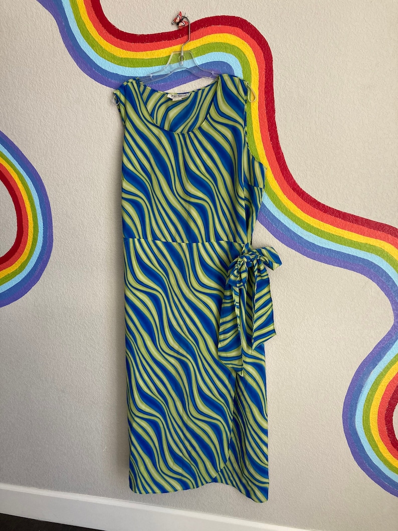 May include: A blue and green sleeveless maxi dress with a wavy stripe pattern. The dress has a wrap style and a tie at the waist.