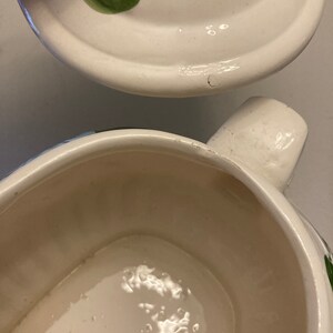 May include: White ceramic serving dish with a green floral design. The dish has a lid with a handle. The dish is empty.