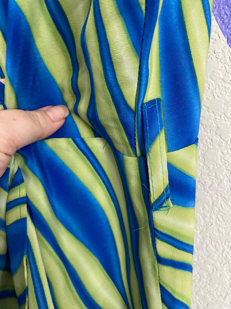 May include: Close-up of a blue and green striped fabric with a seam down the side.