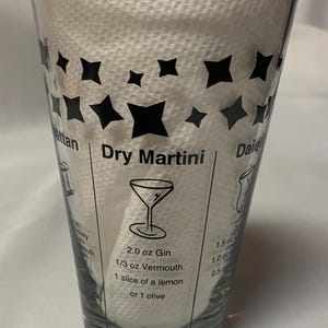 Puede incluir: Un vaso medidor de vidrio transparente con dise&ntilde;os de estrellas negras e instrucciones para hacer un c&oacute;ctel Dry Martini. Las instrucciones incluyen 2,0 oz de ginebra, 1/3 oz de vermut, 1 rodaja de lim&oacute;n o 1 aceituna.