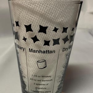 Puede incluir: Un vaso de vidrio transparente con estrellas negras impresas en el lateral. El vaso tiene instrucciones para hacer un c&oacute;ctel Manhattan, incluyendo 1 1/3 oz de whisky, 2/3 oz de vermut rojo, 2 chorros de Angostura, 1 cereza marrasquino y una rodaja de naranja.