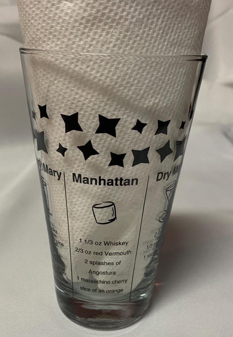 Puede incluir: Un vaso de vidrio transparente con estrellas negras impresas en el lateral. El vaso tiene instrucciones para hacer un c&oacute;ctel Manhattan, incluyendo 1 1/3 oz de whisky, 2/3 oz de vermut rojo, 2 chorros de Angostura, 1 cereza marrasquino y una rodaja de naranja.