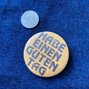 May include: A yellow button with the text "Habe einen guten Tag" in black lettering.