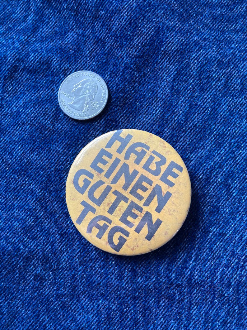 May include: A yellow button with the text "Habe einen guten Tag" in black lettering.