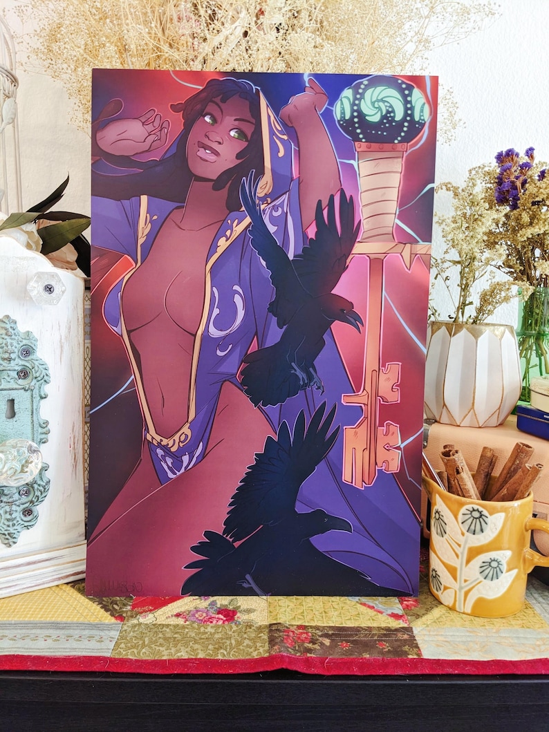 May include: Art print featuring a woman in a purple robe with gold accents, holding a staff with a glowing orb. Two black ravens are in flight. The background is a gradient of red and purple with key-shaped designs.