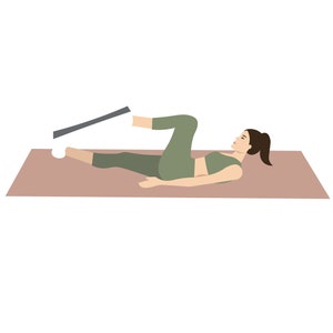 K&ouml;nnte beinhalten: Eine Frau in einem gr&uuml;nen Sport-BH und Leggings liegt auf einer braunen Yogamatte. Sie hebt ein Bein mit einem Widerstandband, das an ihrem Kn&ouml;chel befestigt ist, nach oben.