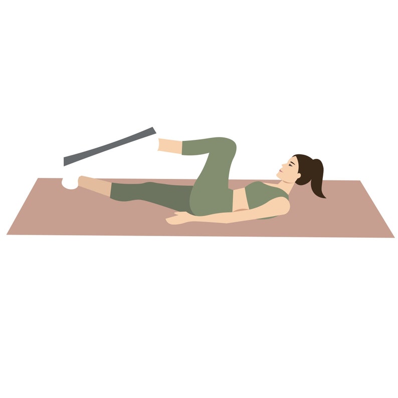 K&ouml;nnte beinhalten: Eine Frau in einem gr&uuml;nen Sport-BH und Leggings liegt auf einer braunen Yogamatte. Sie hebt ein Bein mit einem Widerstandband, das an ihrem Kn&ouml;chel befestigt ist, nach oben.