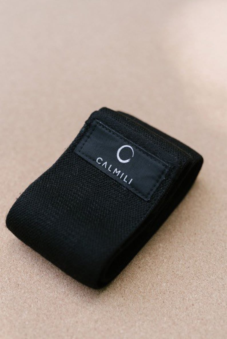 K&ouml;nnte beinhalten: Schwarzes Stoff-Widerstandsband mit dem Text "CALMILLI" und einem Kreislogo.