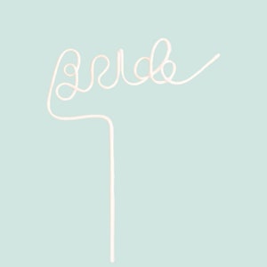 May include: White plastic straw bent into the word "bride" on a light blue background.