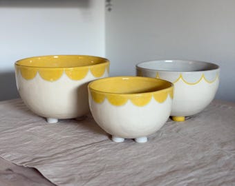 Cuencos apilables de gres hechos a mano, esmalte crema amarillo con vetas onduladas y detalles azules craquelados.