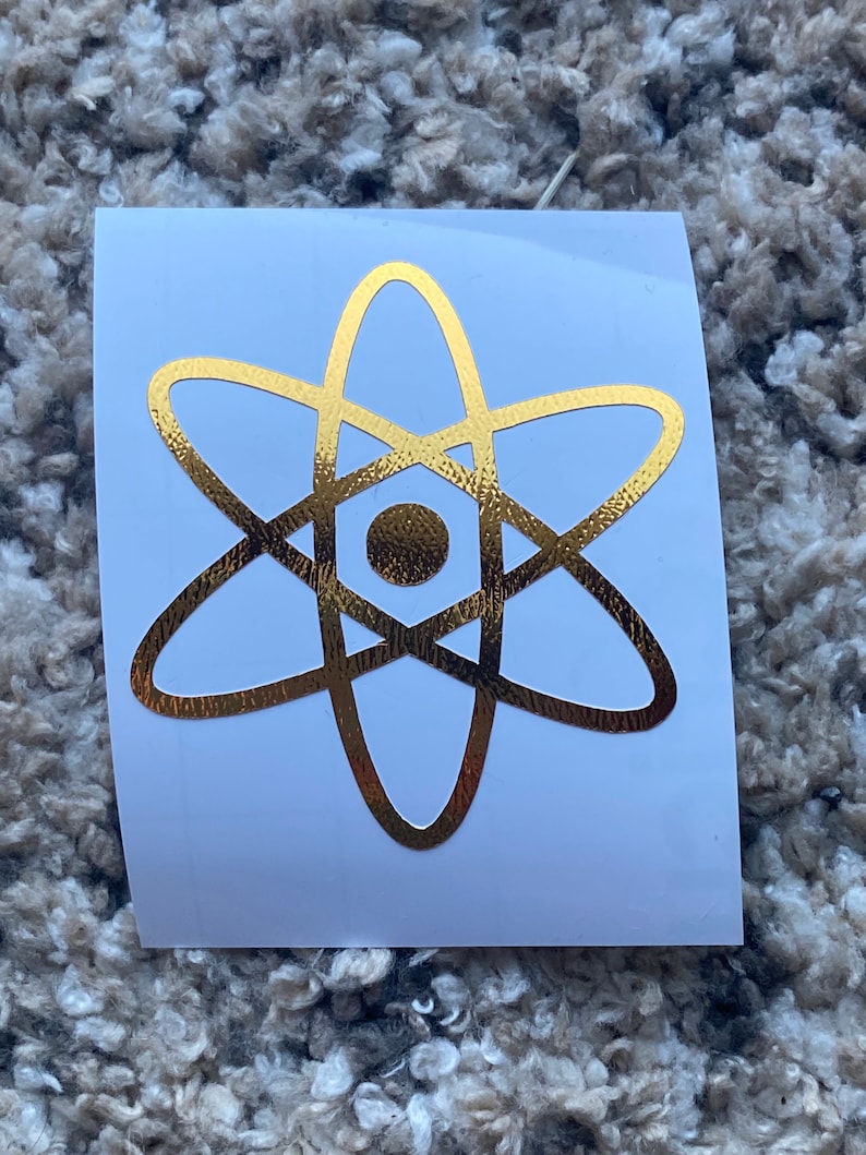 Może przedstawiać: Złota naklejka z symbolem atomu na białym tle.