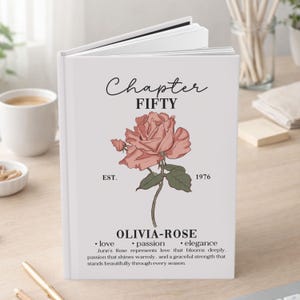 May include: A white journal with the text "Chapter FIFTY" and "OLIVIA-ROSE" with a pink rose illustration. The journal also includes the year "1976" and the words "love, passion, elegance".