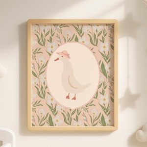 May include: A framed print featuring a whimsical illustration of a goose wearing a pink hat, set within an oval. The background is a floral pattern in pink and white, framed by a light wood border. The artwork is designed for a nursery.