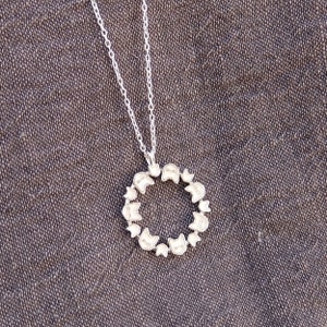 May include: A silver necklace with a circular pendant featuring a repeating pattern of cat faces.
