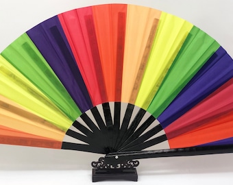 May include: A vibrant, rainbow-colored hand fan. The fan features a black wooden handle and frame, with a decorative base. The fan's panels display a spectrum of colors, including red, orange, yellow, green, blue, and purple.