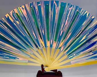 May include: A blue and green iridescent folding fan with a bamboo handle. The fan is open and standing on a wooden stand.
