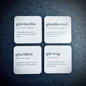 Puede incluir: Cuatro posavasos cuadrados blancos con texto negro que define palabras humorísticas relacionadas con el gin. Las palabras son ginvincible, gintellectual, gincident y gin.wag. Cada palabra tiene una pronunciación fonética y una definición.