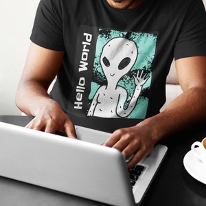 May include: A black t-shirt with a graphic of a grey alien waving with the text "Hello World" printed on the side.