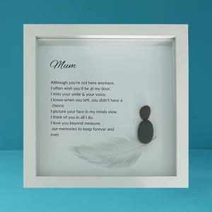Op de afbeelding: Wit omkaderd gedenkkunstwerk met het woord "Mum" bovenaan. De tekst bevat een gedicht over het missen van een geliefde. Een veer en twee kiezelsteenfiguren zijn ook afgebeeld.