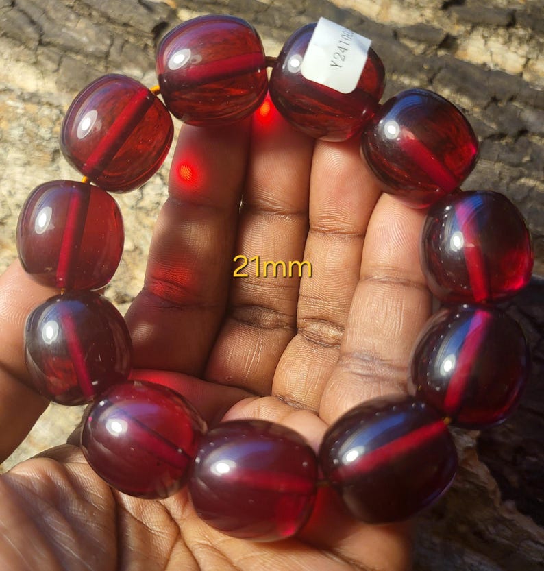 May include: A red, round bead bracelet with 21mm beads. The bracelet is made of glass and has a shiny finish.