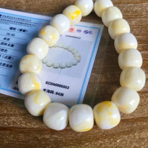 May include: A white and yellow amber bracelet with a certificate of authenticity. The certificate includes the text "62206000412", "622060005503", and "查询码: 8438".