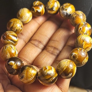 May include: A bracelet made of round, brown and white patterned beads. The beads have a swirling, marbled appearance.