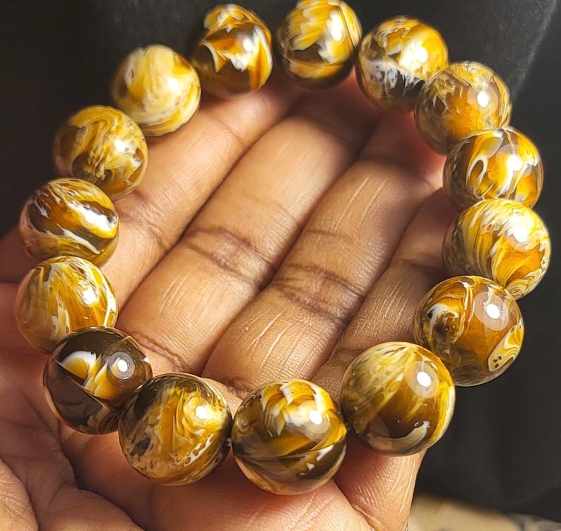 May include: A bracelet made of round, brown and white patterned beads. The beads have a swirling, marbled appearance.