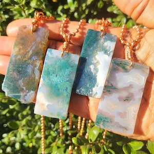 May include: Four copper chain necklaces with rectangular green, white, and brown agate pendants. The pendants have a natural, marbled pattern.