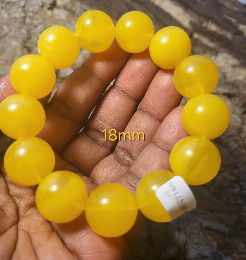 May include: A yellow beaded bracelet with 18mm beads. The bracelet is made of round, smooth beads.