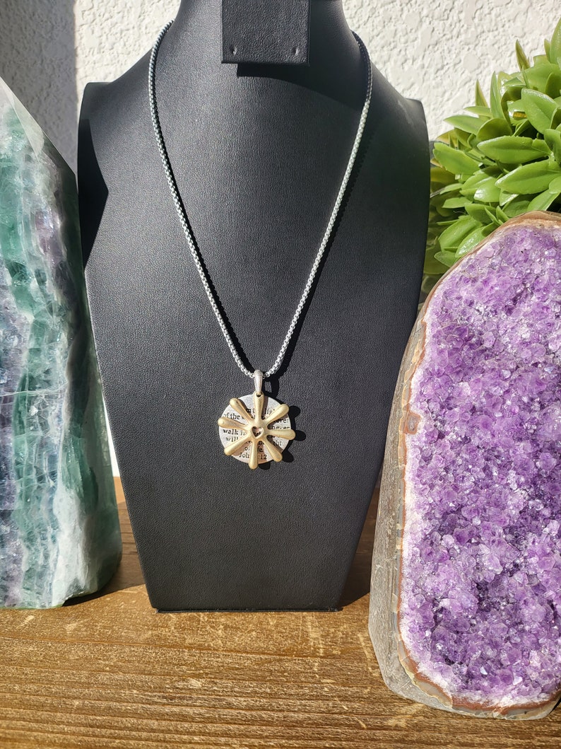 May include: A silver chain necklace with a gold pendant featuring a heart and the words "walk in the light" on a circular background.