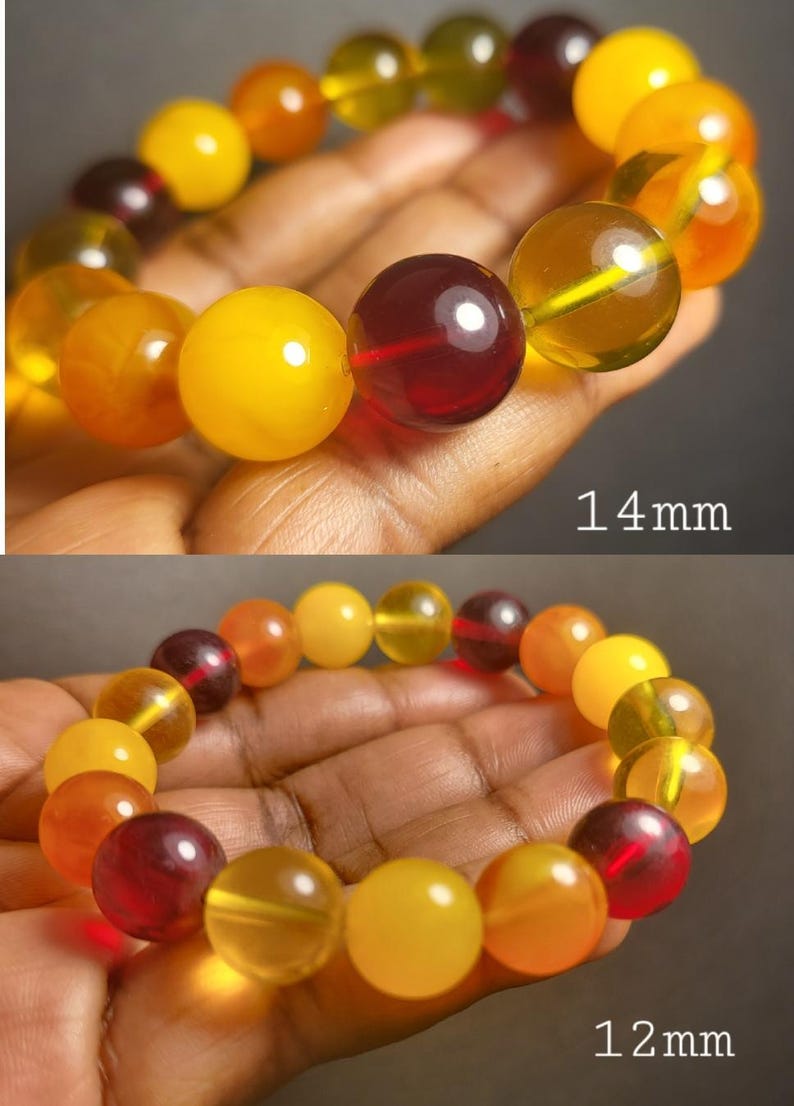 May include: A bracelet made of amber beads in shades of yellow, orange, and red. The beads are round and have a smooth, polished finish. The bracelet is 14 mm wide and 12 mm wide.
