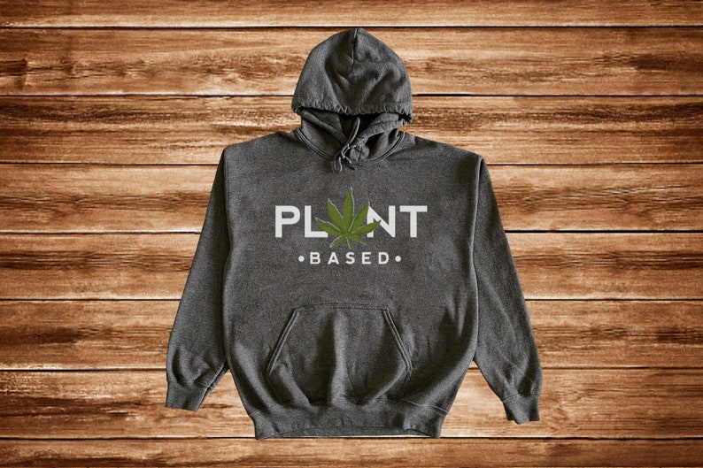 May include: A dark gray hooded sweatshirt with a white graphic that says "PLANT BASED" with a green marijuana leaf in the middle of the word "PLANT".