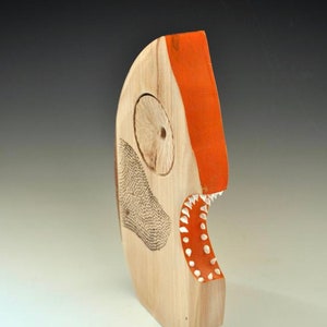 Puede incluir: Una escultura de madera de un pez con la boca abierta, pintada de naranja y blanco. El pez tiene un ojo grande y una fila de dientes.