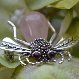 May include: A silver bee brooch with pink quartz wings and ruby eyes. The bee is detailed with textured wings and a textured body.
