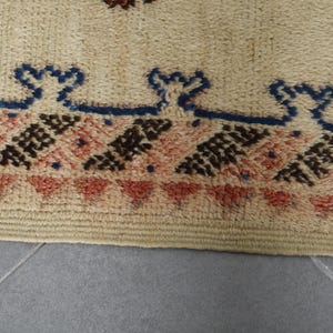 a close-up view of a beige rug with a geometric pattern in shades of red, brown, and blue.