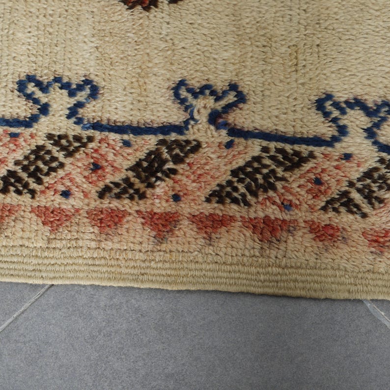 a close-up view of a beige rug with a geometric pattern in shades of red, brown, and blue.