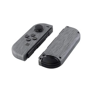Może przedstawiać: Para kontroler&oacute;w Nintendo Switch Joy-Con w kolorze szarym z wzorem drewna. Lewy Joy-Con ma przyciski i joystick, a prawy Joy-Con ma czarny przycisk.