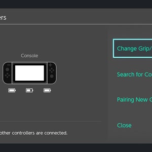 Puede incluir: Una pantalla gris oscuro muestra el men&uacute; "Mandos". Las opciones incluyen "Cambiar agarre/orden", "Buscar mandos" y "Emparejar nuevos mandos". Se muestra un gr&aacute;fico de consola con iconos de bater&iacute;a. El texto dice "No hay otros mandos conectados".