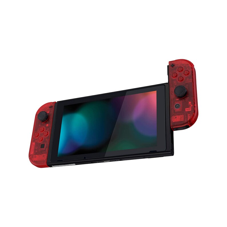 Puede incluir: Una consola Nintendo Switch transparente roja con botones negros y una pantalla negra. La consola est&aacute; en modo port&aacute;til con el Joy-Con derecho desprendido.