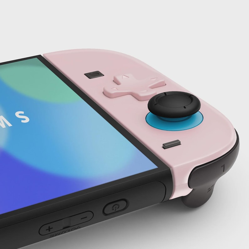 May include: A close-up of a pink and black game controller. The controller has a black joystick with a blue ring, a directional pad, and several buttons. The screen displays a blue and white image.