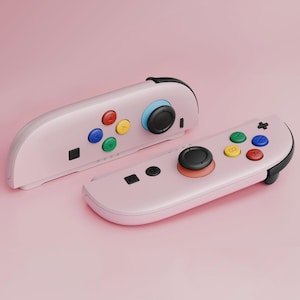 May include: Two pink game controllers with black accents and colorful buttons. The controllers have a variety of buttons in red, yellow, green, and blue. The joysticks are black with a blue and orange accent.