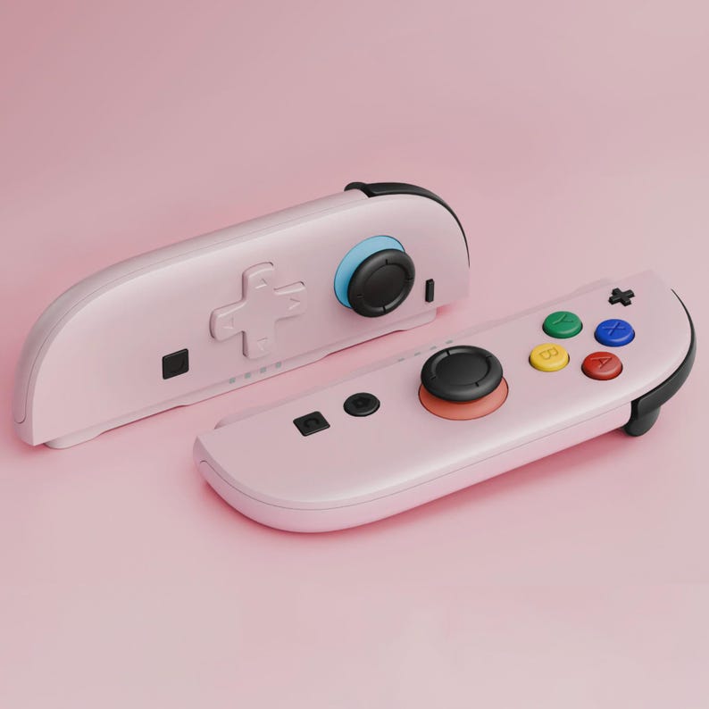 May include: Two pink game controllers with black accents and colorful buttons. One controller has a directional pad, while the other has a joystick and colored buttons. The controllers are set against a pink background.