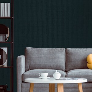 May include: A gray sofa with a yellow throw pillow sits in front of a dark teal wall. A white coffee table with a teacup and saucer and a sugar bowl sits in front of the sofa.