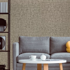 May include: A gray fabric sofa with a yellow throw pillow sits in front of a wall with a beige textured wallpaper. A small round table with a white top and wooden legs sits in front of the sofa. There are two white ceramic cups and a white ceramic sugar bowl on the table.